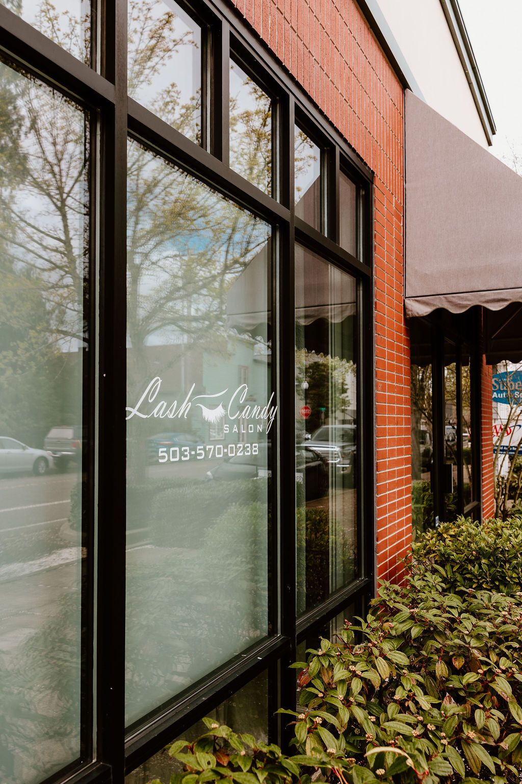 The salon's front window with the Lash Candy Salon logo and phone number