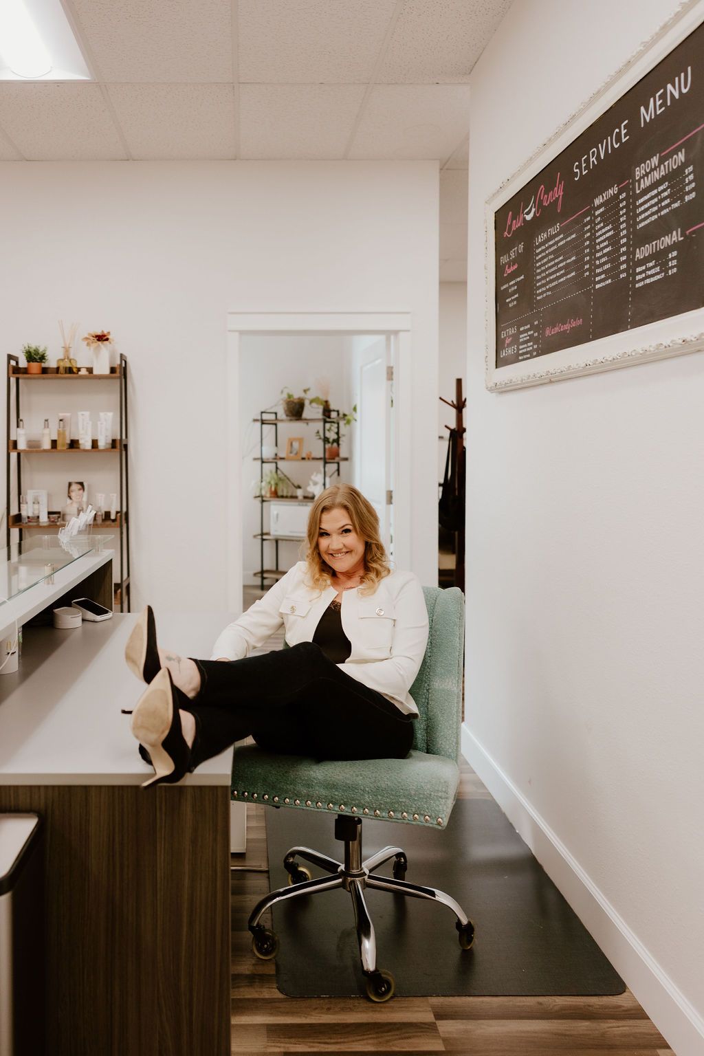 Salon owner relaxing with her feet up at the front desk under the service menu
