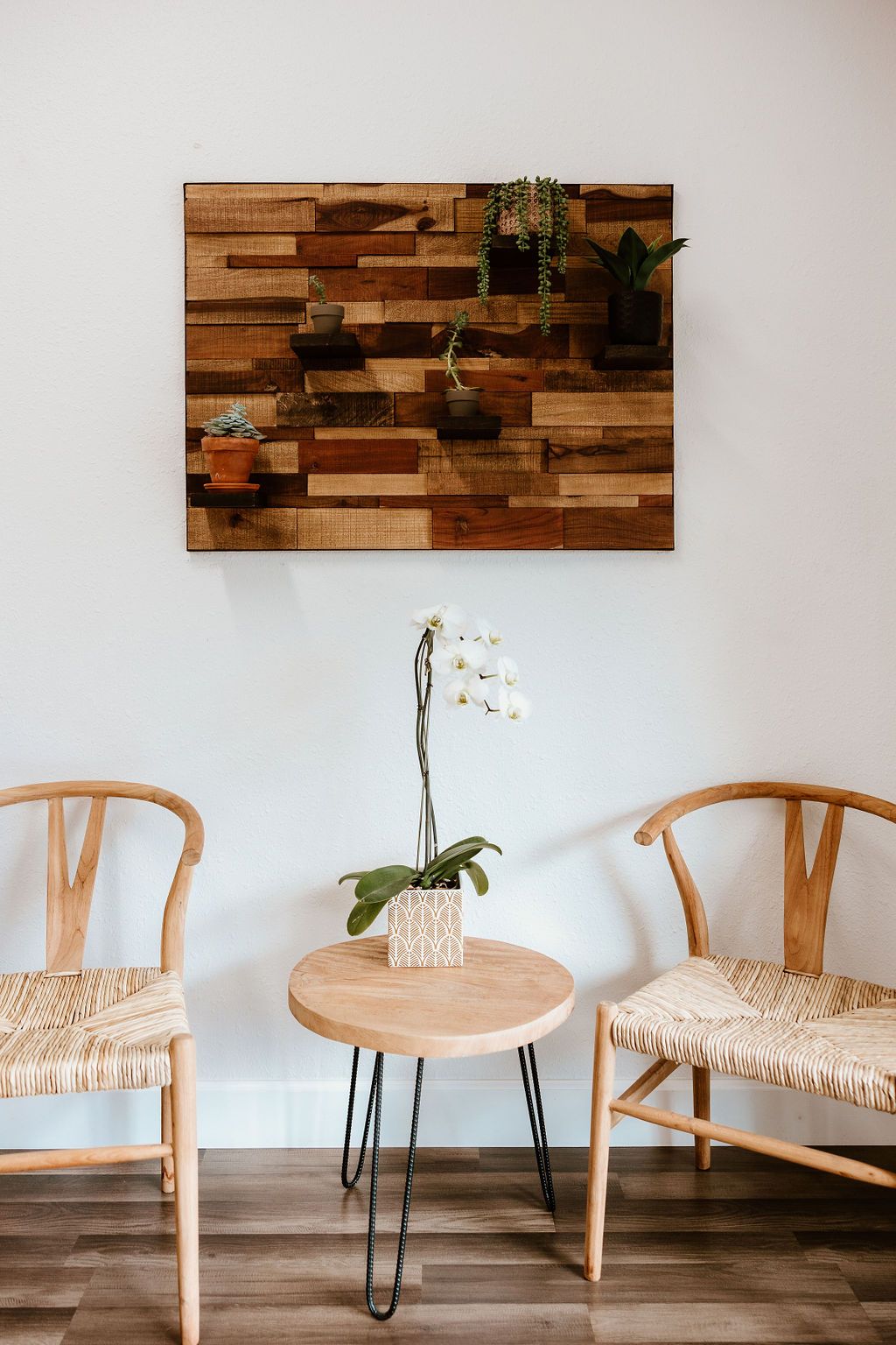Two woven chairs, an orchid and wood wall art in the waiting area